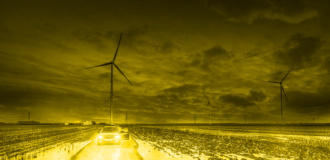 Auto vor dunklem Windpark bei Nacht